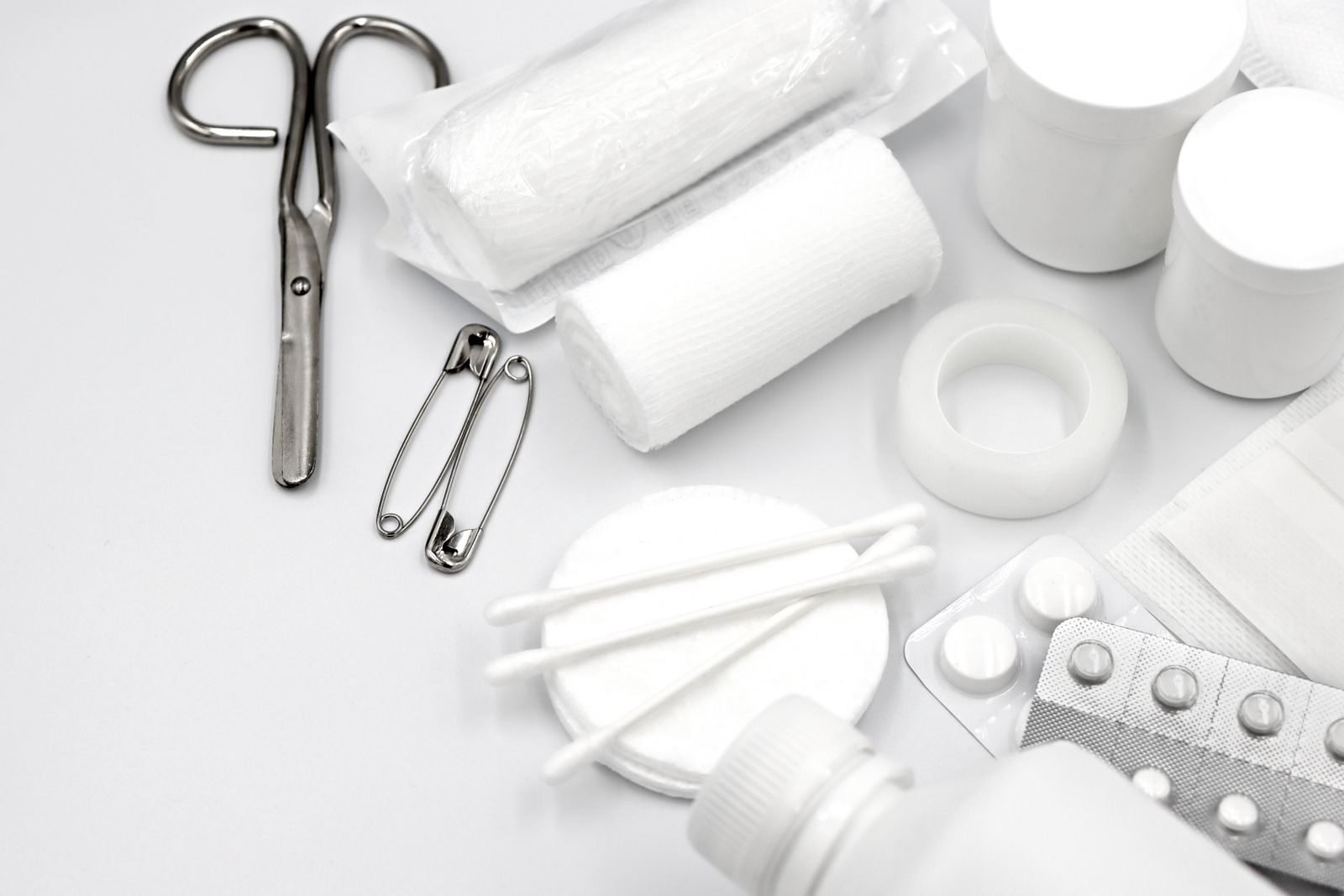 A detailed flat lay of essential first aid supplies including bandages, scissors, and pills.